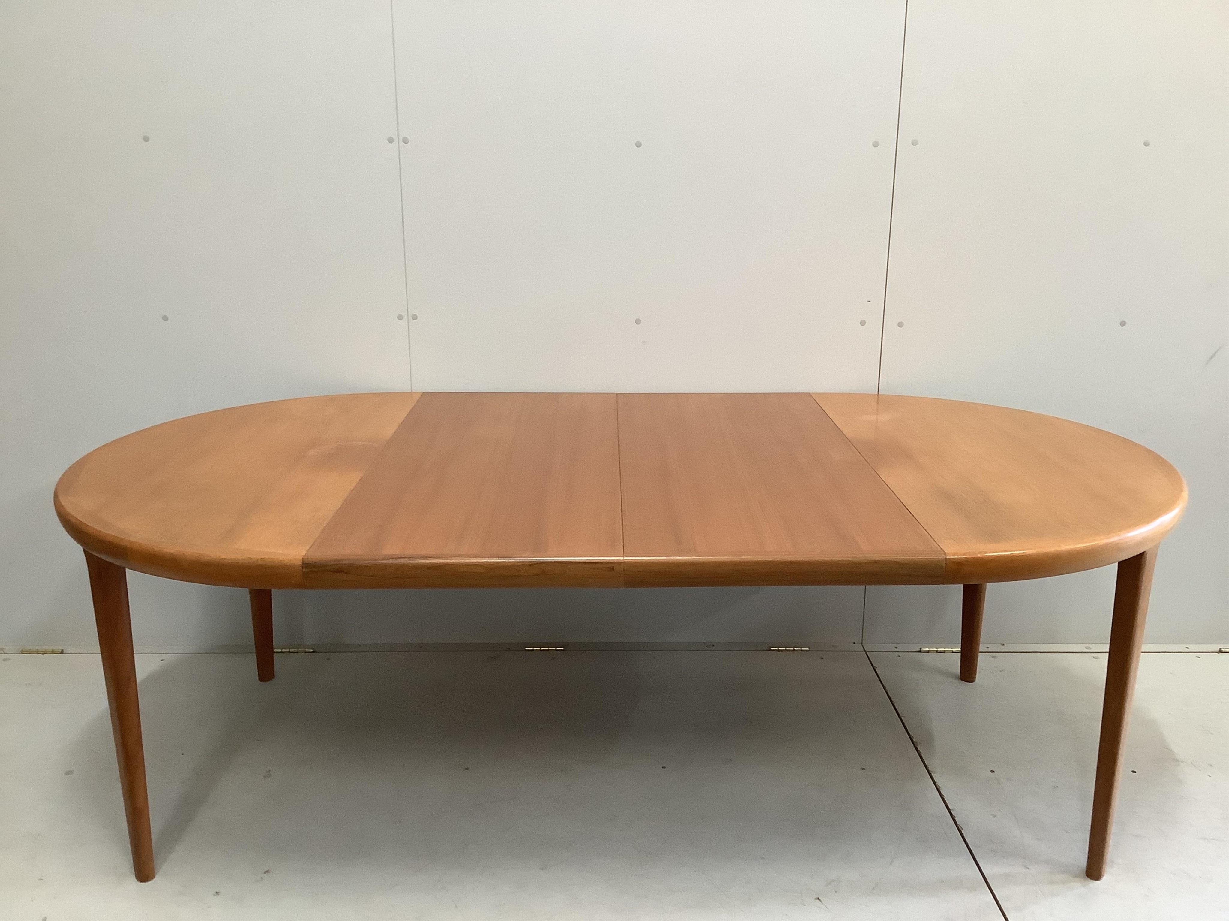 A mid century teak oval extending dining table, width 220cm extended, two spare leaves, depth 120cm, height 72cm and six chairs